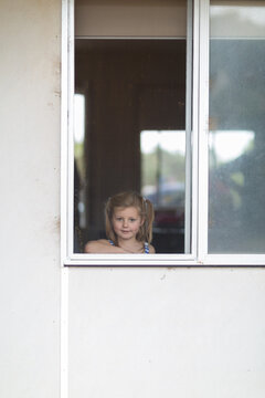 Child looking out window through flyscreen