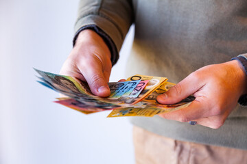 Person's hands on white holding australian notes,cash for paying money