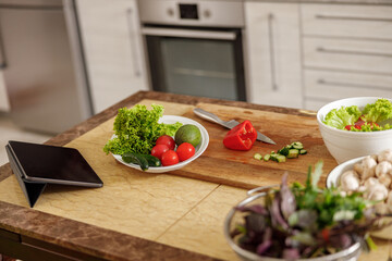 Beautiful smily handsome woman is preparing tasty fresh healthy salad at her kitchen at home