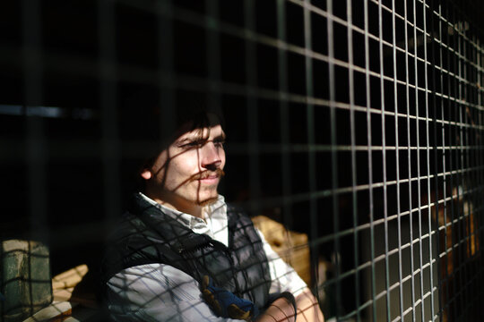 Young Disabled Man Looking out Through Wire Grate