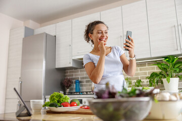 Beautiful smily handsome woman is preparing tasty fresh healthy salad at her kitchen at home