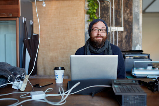 Hipster man with beanie and beard using laptop at work