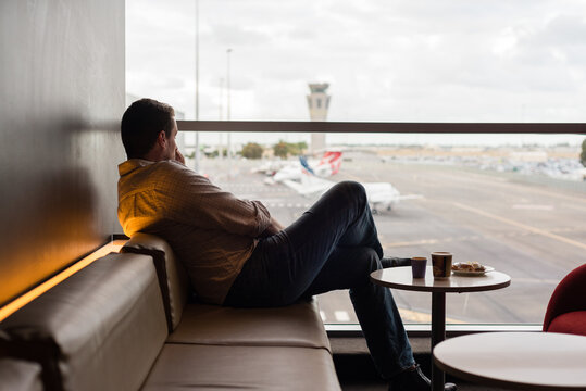 man using phone whilst waiting in airport lounge