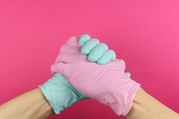 hands in medical surgical gloves different color locked together, joint fight against epidemic, mutual aid, tolerance