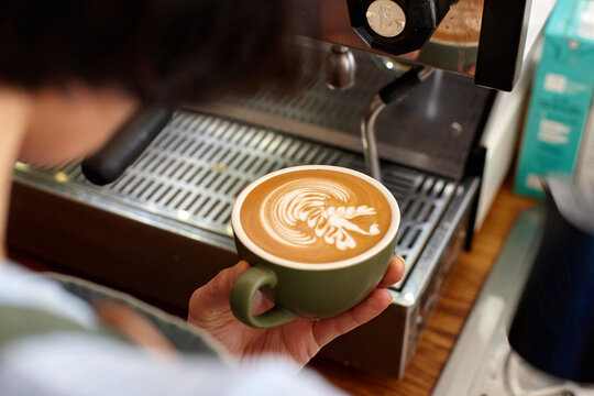 Young female barista preparing coffee with coffee machine