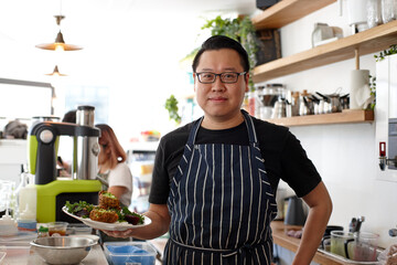 Asian chef working in kitchen at organic food cafe