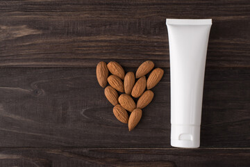 Top flat lay above overhead close up view photo of white label bottle of cream with almond nuts isolated over brown color timber background