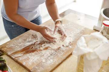 Beautiful smily handsome woman is preparing tasty fresh italian pizzawith vegetables at her kitchen at home