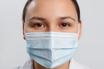 Close-up portrait of a woman covering her face with a medical blue mask, protecting against an outbreak of the coronavirus pandemic infectious disease COVID-19.