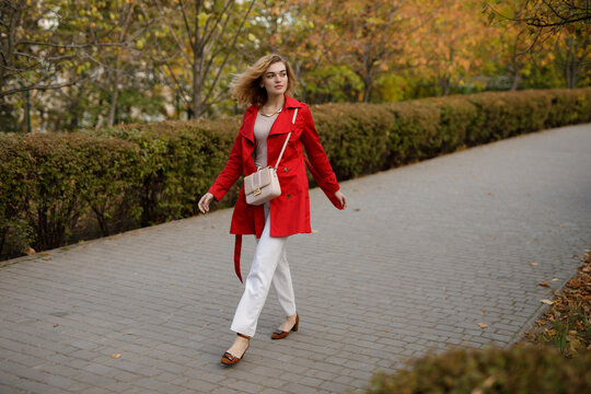 Woman in red coat walks along autumn alley