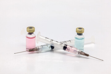 Two different isolated glass vaccine bottles with different colored liquid and two full of colored liquid syringes