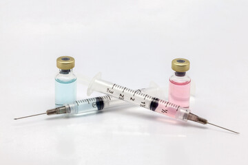 Two different isolated glass vaccine bottles with different colored liquid and two full of colored liquid syringes
