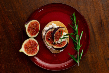 Fig dish with bread, rosemary and cream cheese on a plate