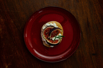 Fig dish with bread, rosemary and cream cheese on a plate