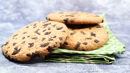 American chocolate chip cookies on a green napkin on a gray background. Traditional round crispy dough with chocolate chips. Bakery. Delicious dessert, pastries.