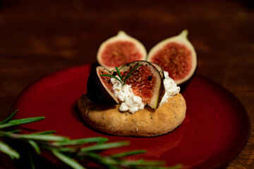 Fig dish with bread, rosemary and cream cheese on a plate