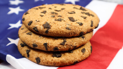 Patriotic cookies. Three rounded traditional chocolate chip cookies on the background of the flag of the United States of America. Delicious sweet pastries, dessert. America's favorite treat.