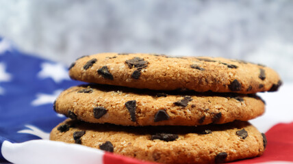 Patriotic cookies. Three rounded traditional chocolate chip cookies on the background of the flag of the United States of America. Delicious sweet pastries, dessert. America's favorite treat.