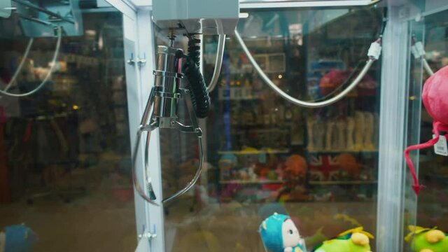 Moving forceps of the claw crane machine. Unsuccessful attempt to grab a toy. Probability of losing a game of chance.