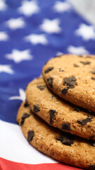 Patriotic cookies. Three rounded traditional chocolate chip cookies on the background of the flag of the United States of America. Delicious sweet pastries, dessert. America's favorite treat.