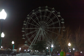 Ferris wheel against the night sky, in the foreground street lights