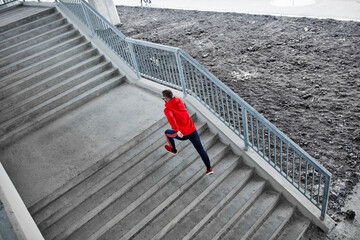 Aerial view of fast runner in shape running on stairs under the bridge.