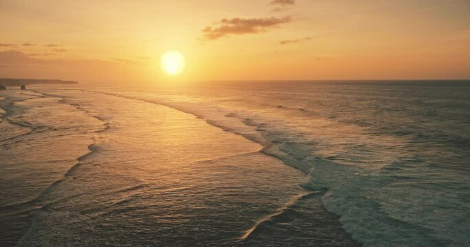 Slow motion of ocean waves at sun set light aerial view. Sunset wavy seascape at tropical paradise resort of Sumba Island, Indonesia, Asia. Cinematic nobody nature scenery at soft sunlight drone shot