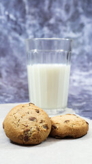 American gluten free chocolate chip cookies with glass glass of vegetable milk on gray background. Chocolate chip cookies. Sweet pastries, dessert. Culinary background. Vertical photography.