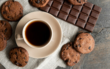 Coffee cup with cookies and chocolate on wooden table background. Mug of black coffee with chocolate cookies. Fresh coffee beans.