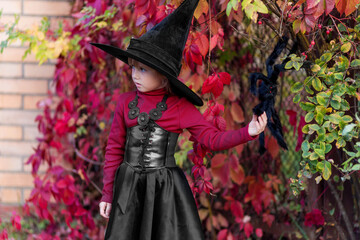 Little girl in witch costume posing on halloween party.