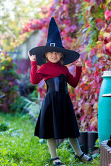 Little girl in witch costume posing on halloween party.