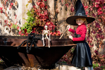 Little girl in a witch costume interferes with a potion on a halloween party