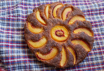 crispy almond pie with peaches on a checkered tablecloth