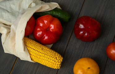 Zero waste concept. Pepper, tomato, corn, cucumber in reusable shopping eco friendly cotton fabric bags. Vegetables in eco bag on a wooden table. Plastic free concept.