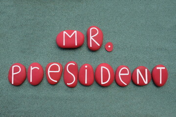 Mister President text composed with red colored stone letters over green sand