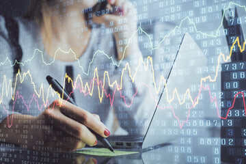 Double exposure of woman hands typing on computer and financial graph hologram drawing. Stock...