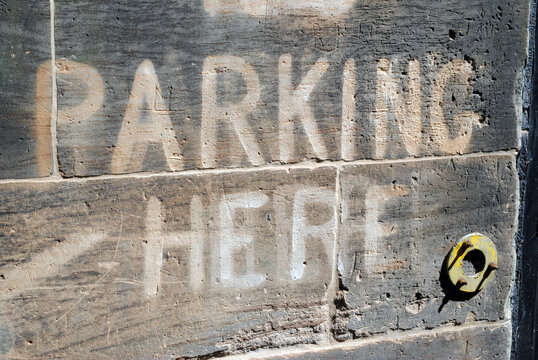 Close Up of Wall with Old Faded 'Parking Here' Sign Painted on Stone Blocks 