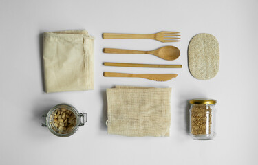 Zero waste kit. Set of eco friendly bamboo cutlery, mesh cotton bags, glass jars and loofah sponge. Plastic free. Natural and reusable items accessories on gray surface.