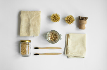 Zero waste kit. Set of eco friendly cleaning brushes, mesh cotton bags, glass jars with a nuts and bamboo toothbrushes. Natural and reusable items accessories on gray surface.