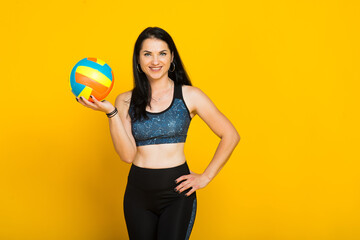 Young beautiful volleyball player isolated on yellow in studio