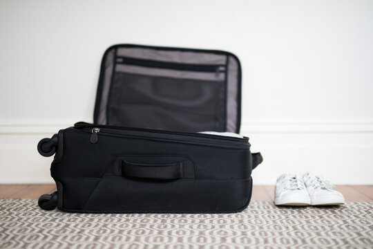 Small overnight weekender black suitcase with wheels packed with clothes,