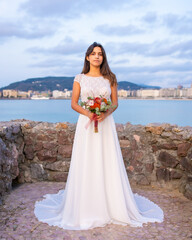 Fototapeta na wymiar Portrait of young caucasian girl in white wedding dress on her wedding day by the sea
