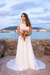 Fototapeta na wymiar Portrait of young caucasian girl in white wedding dress on her wedding day by the sea