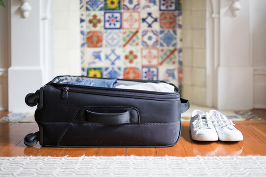Small black overnight weekender travel suitcase wheels packed clothes shoes explore holiday travel timber floor vintage tiles fireplace