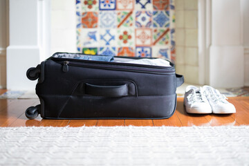 Small overnight weekender black suitcase with wheels packed with clothes,