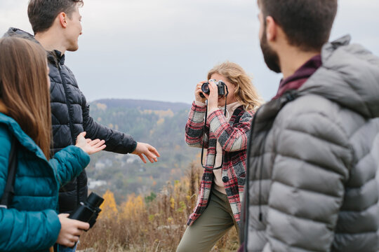 Girl taking pictures of friends in mountains while hiking