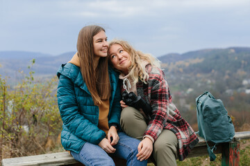 Girlfriends are resting on a bench in the mountains