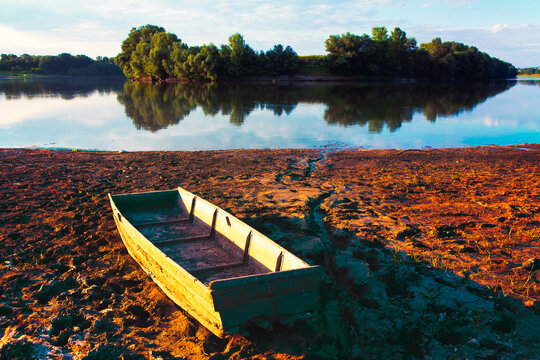 Fishing barque on the dirty shore . Old wooden boat on the muddy riverside