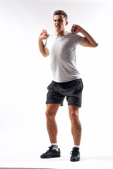 A sports man in shorts and a full-length T-shirt does exercises on a light background