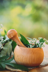 wooden mortar with pestle close-up. White fresh valerian flowers in alternative medicine as a...